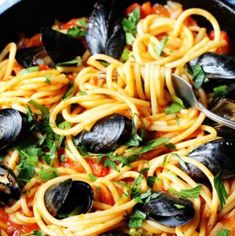 a skillet filled with spaghetti and mussels