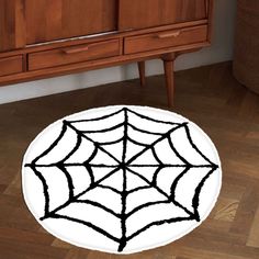 a spider web rug is on the floor in front of a wooden cabinet and dresser