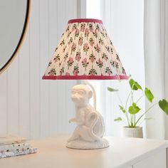 a lamp that is sitting on top of a table next to a mirror and potted plant