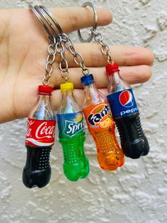 four soda bottles are hanging from a key chain