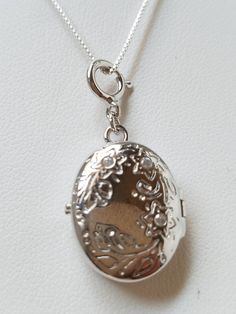 "This Sterling Silver Locket is hand assembled onto a 16\" 925 box chain. The locket has a beautiful floral pattern with 2 clear rhinestones above probably to indicate which way to wear. It is oval shaped hinged locket. On the inside hallmark: \"Toni 925 China\" . This item is new but hand assembled. Locket measures: 1\" L X 5/8\" W Box Chain measures: 16\" Material: Sterling Silver Locket and Chain Come in a gift box with tracking" Oval Silver Chain Jewelry, Elegant Pendant Locket Necklace, Oval Sterling Silver Locket Necklace Nickel Free, Elegant Round Pendant Locket Necklace Stamped 925, Silver Oval Locket Necklace Nickel Free, Silver Oval Locket Necklace For Anniversary, Elegant Silver Locket Necklace Stamped 925, Elegant Pendant Locket Necklace Stamped 925, Silver Locket Necklace With Adjustable Chain For Wedding