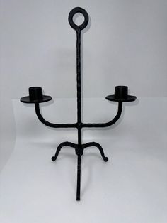 a black candle holder with two candles on it's sides and a hat hanging from the top