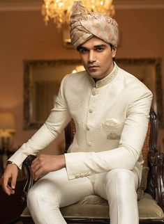 a man in a turban is sitting on a chair and posing for the camera