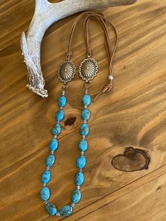 "Southwestern silver concho necklace with luscious blue turquoise beads suspending from adjustable light brown leather lace. These awesome conchos have delicate scalloped edges with an \"Old West\" design giving it a vintage but feminine touch. They are upcycled from a southwestern concho belt. Silver daisy spacers beads separate the turquoise. Tied to the conchos are light brown suede lace. Western design silver bead slides to adjust to your desired length. Silver metal conchos - NOT sterling s Southwestern Adjustable Lariat Turquoise Necklace, Adjustable Southwestern Turquoise Lariat Necklace, Southwestern Lariat Turquoise Necklace, Southwestern Adjustable Turquoise Lariat Necklace, Adjustable Beaded Rustic Turquoise Necklace, Handmade Western Lariat Necklace, Adjustable Concho Necklaces For Festival, Western Lariat Jewelry For Festival, Vintage Concho Lariat Necklace