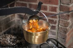 a pot filled with food sitting on top of a stove next to a brick wall