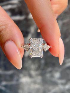 a woman's hand holding an engagement ring with three diamonds on it and the center diamond in the middle