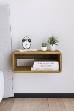 a wooden shelf with two books and a clock on it