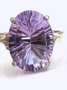 "A BIG, beautiful, flawless purple genuine Brazilian Amethyst concave cut oval stone, 16 mm x 12 mm in size. It is set in a sterling silver cathedral setting. The stone weighs about 9.5 carats. The ring is stamped \"925\" and is guaranteed to be sterling silver. The stone is flawless - the picture contains artifact. The silver ring appears to have a gold tint in the photo but is in fact bright silver. Your ring will be polished and smooth. Size selectable above. Some sizes may take up to 2-3 weeks to prepare." Luxury Purple Amethyst Oval Cabochon Ring, Classic Luxury Cabochon Amethyst Ring, Luxury Formal Amethyst Ring, Oval Cabochon, Elegant Silver Amethyst Ring, Oval Cabochon, Luxury Amethyst Cabochon Ring Collectible, Silver Halo Ring, Rainbow Topaz, Cathedral Setting, Amethyst Gem