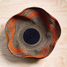 an orange and black basket sitting on top of a wooden table