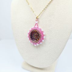 Add a touch of elegance and charm to your outfit with this beautiful handmade beadwork glass pendant!  Hand woven pendant features a stunning Czech pressed glass rosette cabochon surrounded by intricate beadwork featuring fine Miyuki glass seed beads and sparkling crystal rondelle beads. The pendant hangs delicately from a Gold-plated Stainless Steel chain. Whether you're dressing up for a special occasion or simply adding a pop of color to your everyday look, this pendant is sure to turn heads and spark joy wherever you go!  Each piece is lovingly crafted by hand, making it a unique and special addition to your jewelry collection. Treat yourself or surprise a loved one with this one-of-a-kind piece that is sure to gather compliments! 👉  Hand beaded by CyntheCreations 👉  Measurements:  1 Adjustable Beaded Necklace With Teardrop Pendant, Gift Pendant Beaded Necklace With Tiny Beads, Beaded Czech Glass Pendant Necklace, Handmade Czech Glass Necklace With Round Pendant, Handmade Czech Glass Round Pendant Necklace, Czech Glass Round Pendant Necklaces As Gifts, Czech Glass Round Pendant Necklaces For Gifts, Czech Glass Round Pendant Necklace For Gifts, Czech Glass Round Pendant Necklace As Gift