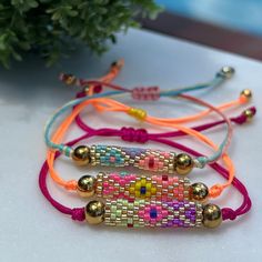 three bracelets with beads on them sitting next to a potted plant in the background