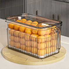 a container filled with lots of oranges on top of a counter next to an oven