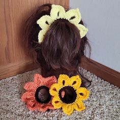 two crocheted flower hair clips on top of a carpeted floor next to a door