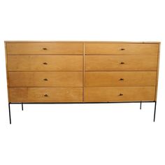 a large wooden dresser with black legs on it's top and bottom drawers, against a white background