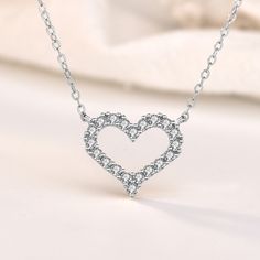 This exquisite piece embodies a perfect blend of elegance and sophistication. Crafted with utmost precision, the heart-shaped pendant is made from sterling silver, radiating a timeless charm. The round cut stones glisten with a captivating brilliance, adding a touch of enchantment to your every ensemble. Wear this mesmerizing necklace as a symbol of love and purity, embracing its graceful beauty close to your heart.Weight: 2.2 gWidth: 15 mmHeight: 13 mmMaterial: 925 SilverPlating Color: SilverLe Hollow Heart, Silver Heart Necklace, Cute Necklace, Necklace Online, Sterling Silver Necklace, Quality Jewelry, Solid 925 Sterling Silver, Heart Necklace, Sterling Silver Necklaces