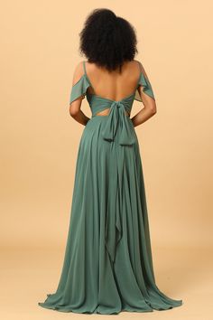 the back of a woman wearing a green dress with an open shoulder and bow at the waist