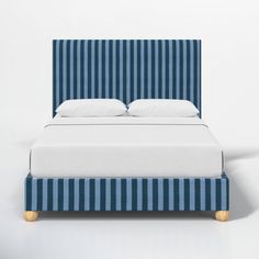 a bed with blue and white striped upholstered headboard