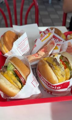 two hot dogs with cheese, ketchup and relish in baskets on a red tray