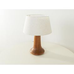 a wooden table lamp with a white shade on it's base and a light bulb in the middle