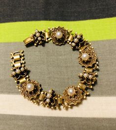 Rare hard to find Coro bracelet from the 1940s with book chain individual links in Victorian style. Floral motifs include simulated seed pearls. Goldtone and with snap clasp. In very good condition. Measures 7.25 inches in length. Antique Gold Bracelet With Antique Finish, Vintage Bronze Bracelet For Formal Occasions, Vintage Bronze Bracelets For Formal Occasions, Vintage Gold Bracelet With Intricate Design, Vintage Gold Bracelets With Antique Finish, Vintage Round Pearl Bracelet For Formal Occasions, Antique Gold Bracelet As Gift, Antique Gold Bracelet Perfect For Gift, Vintage Yellow Gold Pearl Bracelet For Formal Occasions