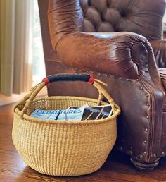 a brown leather chair next to a woven basket