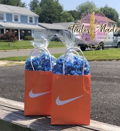 two bags filled with blue candies sitting on top of a wooden bench in front of a house