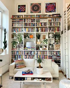 a white couch sitting in front of a book shelf filled with different types of books