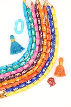 multicolored beaded necklace with tassels and charms on white background, top view