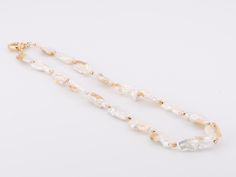 ♥ Natural Gold Infused Biwa Pearl Necklace with Sailor Clasp P1014 ♥ Pearls measure 8 x 22mm for each pearl. ♥ The item measures 18" in length. ♥ All stone(s) used are genuine, earth-mined, and guaranteed conflict free! As is with anything that is naturally occurring, our gemstones or pearls will have imperfections, e.g. inclusions in the gemstones, unevenness in the pearl nacre.♥ Free shipping in the US.♥ This is an in-stock item and ready to ship right away! White Baroque Pearl Long Necklace, Pearl White Shell Necklace With Pearl Chain As Gift, 16 Inch White Pearl Necklace For Gifts, White Mother Of Pearl Necklace With Pearl Pendant, White Mother Of Pearl Pendant Necklace, White Pearl Charm Necklace In Mother Of Pearl, White Pearl Pendant Long Necklace, White Single Strand Mother Of Pearl Beaded Necklaces, White Beaded Necklaces With Pearl Pendant