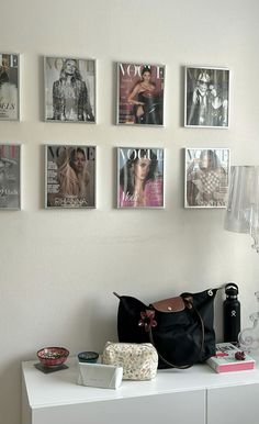 a white table topped with a black purse and pictures hanging on the wall above it