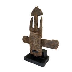 an old wooden sculpture with geometric designs on it's face and hands, sitting on a black stand