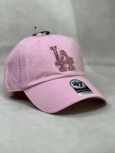 This is a light pink LA Dodgers 47 clean up women's adjustable hat that is hand embellished with matching pink Swarovski style crystals on the front logo. This hat features over 150+ Swarovski style crystals. - 100% Cotton - Matching fabric strap & buckle - One Size Fits All - Raised Embroidered Logo - 150+ Swarovski style pink crystals individually placed by hand - Ready to ship in 1 week from San Diego, CA Cheap Pink Hats With Embroidered Logo, Trendy Snapback Baseball Cap With Rhinestones, Trendy Rhinestone Snapback Baseball Cap, Pink Dad Hat For Streetwear In Spring, Trendy Pink Dad Hat With Curved Visor, Pink Dad Hat For Spring Streetwear, Spring Pink Dad Hat For Streetwear, Spring Streetwear Pink Dad Hat, Adjustable Baseball Cap With Bling