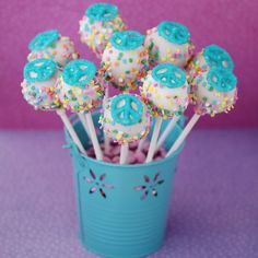 blue and white cake pops with sprinkles in a turquoise cup on a purple table