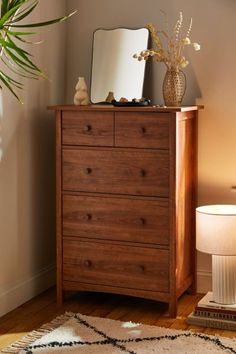 a wooden dresser with a mirror on top of it next to a lamp and potted plant