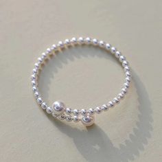 Experience elegance redefined with our "Eternal Embrace" White Freshwater Pearl Bracelet. Two large pearls gracefully frame the open closure, forming a captivating large circle that symbolizes unity and endless beauty. The design's simplicity accentuates the pearls' natural allure, making it a versatile piece suitable for both casual and formal occasions. A classic with a contemporary twist, this bracelet is a timeless addition to any jewelry collection. Pearl size 5-7mm Note: Our jewelry is han Dainty Sterling Silver Pearl Bracelet, Minimalist Silver Round Pearl Bracelet, Minimalist Silver Pearl Bracelet, Minimalist Silver Pearl Chain Bracelet, Adjustable White Gold Bracelets With Pearl Charm, Elegant Hypoallergenic Jewelry With Round Beads, Elegant Sterling Silver Pearl Bangle Bracelet, Pearl Drop Round Bracelets For Anniversary, Silver Stackable Pearl Bracelet With Round Beads