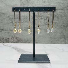 Dangly pearl earrings with hook closure in gold plated stainless steel. These gold pearl earrings come as diamond shaped pearls, rhombus shaped pearls, and oblong oval shaped pearls. They are classic bride earrings, pearl bridesmaid earrings, or dangly earrings for capsule wardrobe.   Also available in Silver: https://etsy.me/3GDblku 🌈 Pair the oblong oval shape with our multicolor gemstone and pearl necklace: https://etsy.me/46imjX1 💥 RUSH ORDER: All of our items are handmade and made to order. Our standard turnaround time is 5-7 days. If you need an item sooner, you can purchase a rush order from our shop here: https://etsy.me/47GuxKo Recommendations for maintaining your natural stone and pearl jewelry: ✅ Wipe with a soft cloth ✅ Store jewelry in a dry and protected place ✅ Take care n Metal Hoop Earrings With Pearl Charm For Gift, Metal Hoop Earrings With Pearl Charm As A Gift, Adjustable Minimalist Pearl Earrings For Pierced Ears, Adjustable Minimalist Pearl Earrings, Minimalist Adjustable Pearl Earrings, Adjustable Pearl Charm Drop Earrings, Adjustable Pearl Charm Earrings As Gift, Adjustable Minimalist Dangle Pearl Earrings, Dainty Adjustable Dangle Pearl Earrings