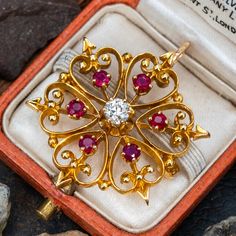 This captivating vintage open work brooch/pendant is centered with a transitional brilliant cut diamond, weighing 0.27 carats, in a six-prong setting. The center is surrounded by six (6) round mixed cut rubies in four-prong settings. The brooch measures 28.9mm long and is finished with a hinged foldable bail and a hinged and locking pin back. Vintage Pendant Brooches With Intricate Design, Vintage Gold Brooch With Intricate Design, Victorian Gold Pendant Brooches, Victorian Yellow Gold Diamond Brooches, Antique Gold Brooch With Gemstone, Jewellery Sketches, Gold Bangles Design, Brooch Jewelry, Bangle Designs