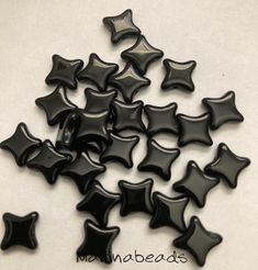 small black stars are scattered on a white surface with the word mama beads written below them