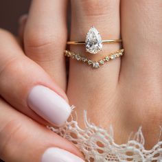 a woman's hand holding a ring with a diamond on it and a white lace