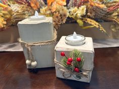 two white candles sitting on top of a wooden table