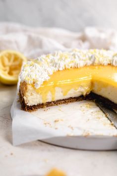 a piece of cheesecake on a white plate with a knife and lemon wedge next to it