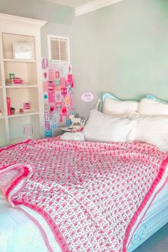 a bed with red and white bedspread in a bedroom next to a book shelf