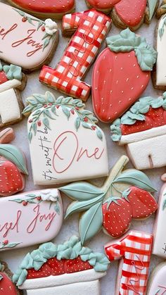 some cookies are decorated like strawberrys and one is for someone's first birthday