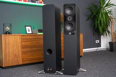 two speakers sitting on top of each other in front of a plant