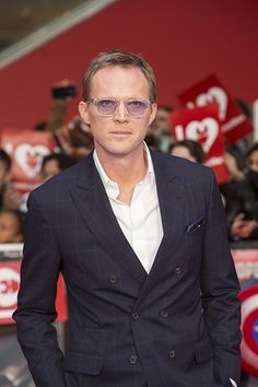 a man in a suit and sunglasses standing on a red carpet