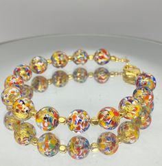 "Murano glass bracelet of 8mm beads with genuine 24k gold foil within each bead. Colorful and whimsical jewelry with an elegant touch! These glass beads are sourced from Artisans in Murano, Italy in Venice where they apply age old techniques to create these tiny works of art. Each bead is so charming with colors of red, orange, blue and yellow splattered within. Tiny gold beads accent the glass beads. The bracelet measures 7.25 inches with a Vermeil gold lobster claw clasp. ( Please measure your Venetian Glass Jewelry, Multicolor Gold Bangle Bracelet As A Gift, Multicolor Bangle Gold Bracelet As A Gift, Round Czech Glass Bracelets With Large Beads, Gold Bangle Bracelet With Colorful Beads, Gold Beaded Bracelets With Large Czech Glass Beads, Elegant Glass Beaded Bracelets As Gift, Adjustable Gold Crystal Bracelet With Large Beads, Gold Bracelets With Large Beads