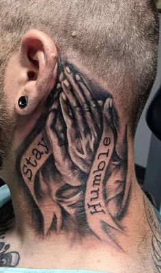 a man with a tattoo on his neck holding hands up to the ground and praying