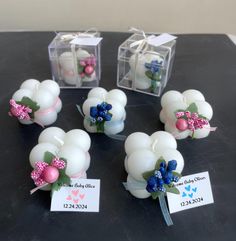 small white candles with pink, blue and green flowers in them on a black table