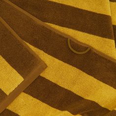 two brown and yellow towels laying next to each other on top of one another with a circular object in the middle