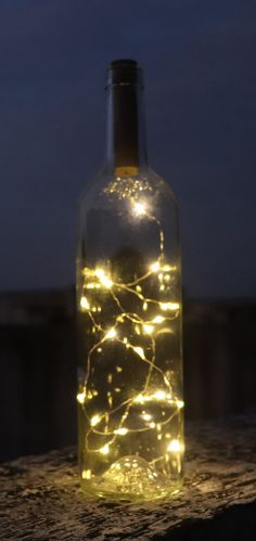 a bottle filled with lights sitting on top of a wooden table